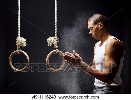Gymnast man powdering hands on rings. View Large Photo Image Stock Image - Gymnast man powdering hands on rings.. Fotosearch