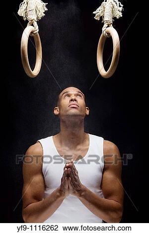 Gymnast man powdering hands on rings. View Large Photo Image Stock Image - Gymnast man powdering hands on rings.. Fotosearch