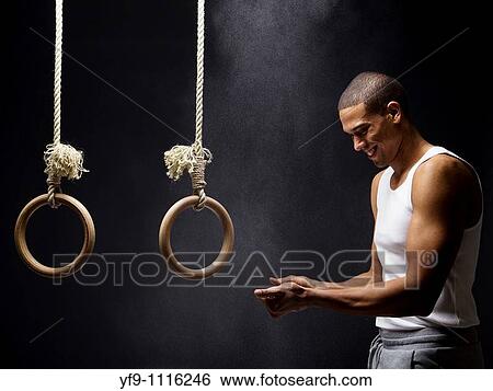 Gymnast man powdering hands on rings. View Large Photo Image Stock Photograph - Gymnast man powdering hands on rings.. Fotosearch