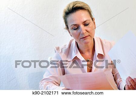 Stock Image - Half body image of caucasian woman reading papers, Hamburg, Germany, Europe.. Fotosearch
