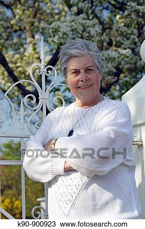 Half body image of elderly caucasian woman wearing a white sweater with crossed arms at sunny weather, smiling and looking into the camera and a blossoming tree in the background, Island of Amrum, Northfrisian, Schleswig_Holstein, Northern Germany, Europe View Large Photo Image Stock Image - Half body image of elderly caucasian woman wearing a white sweater with crossed arms at sunny weather, smiling and looking into the camera and a blossoming tree in the background, Island of Amrum, Northfrisian, Schleswig_Holstein, Northern Germany, Europe. Fotosearch