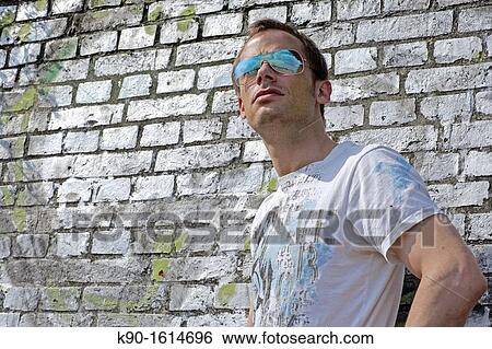 Half body image of young caucasian man, looking cool with sunglasses into the far distance, T-Shirt, seen from front, wall of old white bricks behind him, Hamburg, Germany, Europe View Large Photo Image Stock Photograph - Half body image of young caucasian man, looking cool with sunglasses into the far distance, T-Shirt, seen from front, wall of old white bricks behind him, Hamburg, Germany, Europe. Fotosearch