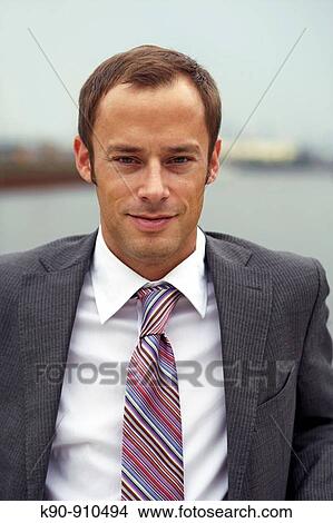 Half body photograph of young, caucasian business man in grey suit and tie, looking friendly smiling into the camera, Hamburg, Germany, Europe View Large Photo Image Picture - Half body photograph of young, caucasian business man in grey suit and tie, looking friendly smiling into the camera, Hamburg, Germany, Europe. Fotosearch
