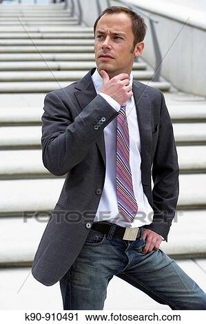 Half body photograph of young, caucasian business man in grey suit, standing on stairs and looking thoughtful to the side with one hand at his chin, Hamburg, Germany, Europe View Large Photo Image Stock Image - Half body photograph of young, caucasian business man in grey suit, standing on stairs and looking thoughtful to the side with one hand at his chin, Hamburg, Germany, Europe. Fotosearch