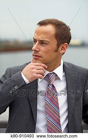 Half body photograph of young, caucasian business man in grey suit, looking thoughtful to the side with one hand at his chin, Hamburg, Germany, Europe View Large Photo Image Stock Image - Half body photograph of young, caucasian business man in grey suit, looking thoughtful to the side with one hand at his chin, Hamburg, Germany, Europe. Fotosearch