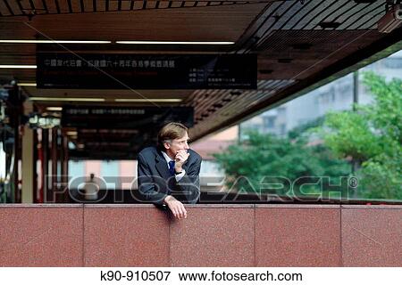 Half body photograph of young, caucasian business man in grey suit, leaning over the balustrade of a building's walkway, looking thoughtful to the side, with one hand supporting his head, Hong Kong, China, Asia View Large Photo Image Stock Photo - Half body photograph of young, caucasian business man in grey suit, leaning over the balustrade of a building's walkway, looking thoughtful to the side, with one hand supporting his head, Hong Kong, China, Asia. Fotosearch