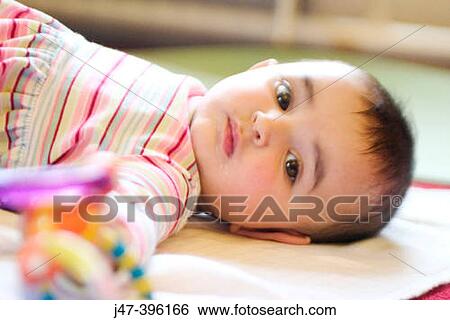 Half cast little girl lying on the floor View Large Photo Image Stock Photograph - Half cast little girl lying on the floor. Fotosearch