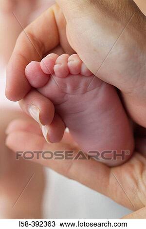 Hand holding feet of newborn baby View Large Photo Image Stock Image - Hand holding feet of newborn baby. Fotosearch