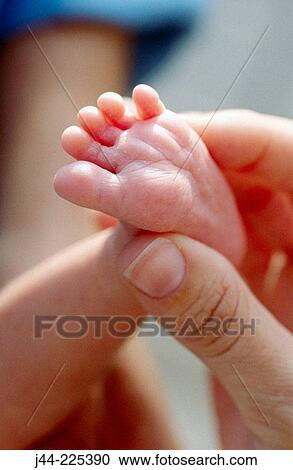 Stock Image - Hand holding foot of newborn baby. Fotosearch