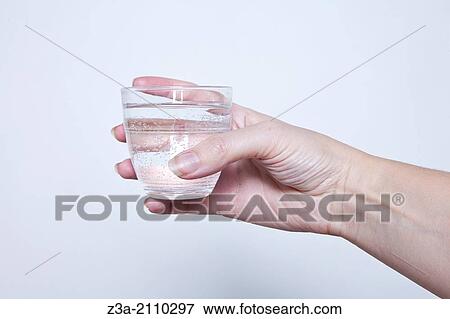Stock Photo - Hand Holding Glass Of Water, Hand Gesture, Studio shot. Fotosearch