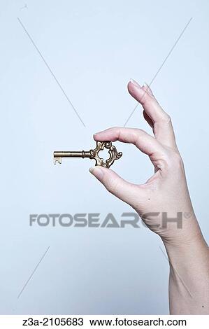 Stock Image - Hand Holding Key, Hand Gesture, Studio shot. Fotosearch