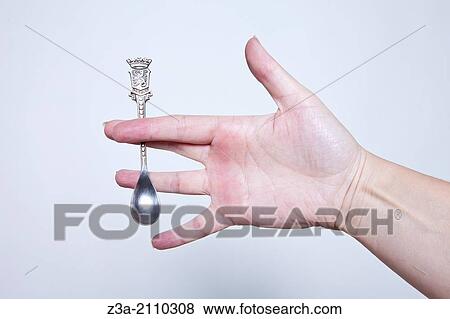 Stock Photo - Hand Holding Little Antique Silver Spoon, Hand Gesture, Studio shot. Fotosearch