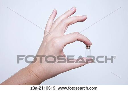 Stock Photo - Hand Holding Little Glass Bottle, Hand Gesture, Studio shot. Fotosearch