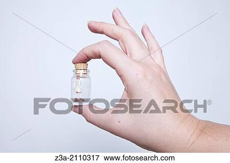 Hand Holding Little Glass Bottle With Tiny Woman In It, Hand Gesture, Studio shot View Large Photo Image Stock Photo - Hand Holding Little Glass Bottle With Tiny Woman In It, Hand Gesture, Studio shot. Fotosearch