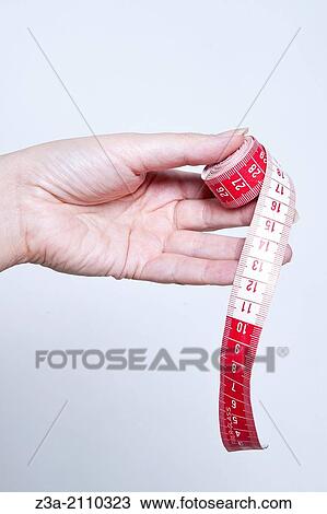 Stock Image - Hand Holding Measuring Tape, Hand Gesture, Studio shot. Fotosearch