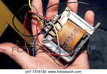 Stock Image - hand holding old fashioned transformer with wires protruding. Fotosearch