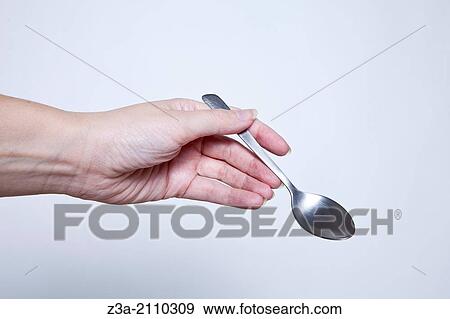 Stock Photo - Hand Holding Silver Spoon, Hand Gesture, Studio shot. Fotosearch