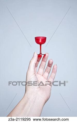 Stock Photography - Hand holding small red cocktail glass.. Fotosearch