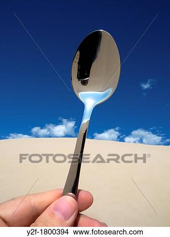 hand holding teaspoon that reflects sky in sand dunes View Large Photo Image Picture - hand holding teaspoon that reflects sky in sand dunes. Fotosearch
