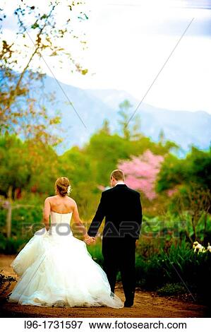 hand in hand, this happy married couple heads to their romantic garden reception to celebrate View Large Photo Image Stock Photo - hand in hand, this happy married couple heads to their romantic garden reception to celebrate. Fotosearch