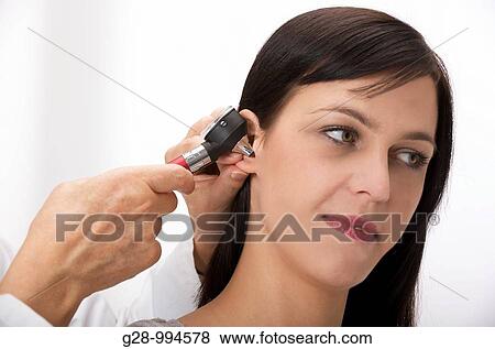 hand of doctor in white gown holding an otoscope and examining a young woman? s ear View Large Photo Image Stock Photo - hand of doctor in white gown holding an otoscope and examining a young woman? s ear. Fotosearch