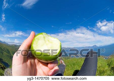Hand of hiker holding partially eaten apple on mountain top, Lofoten islands, Norway View Large Photo Image Stock Photography - Hand of hiker holding partially eaten apple on mountain top, Lofoten islands, Norway. Fotosearch