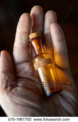 Stock Image - hand showing empty bottle of homeopathy. Fotosearch