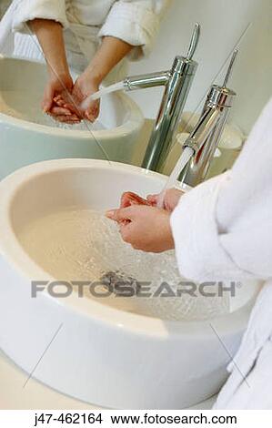 Picture - Hands and their reflection under running tap at the sink. Fotosearch