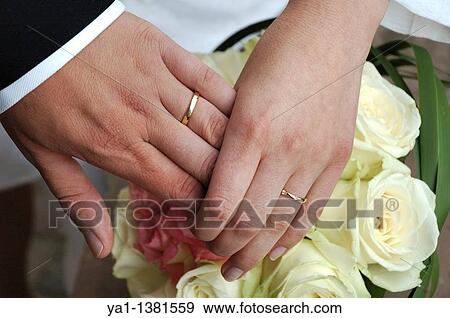 Stock Photo - Hands of brides over roses bouquet, France. Fotosearch