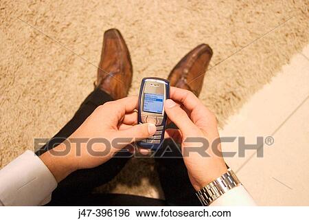 Hands on mobile phone, 2 feet in background View Large Photo Image Stock Photograph - Hands on mobile phone, 2 feet in background. Fotosearch