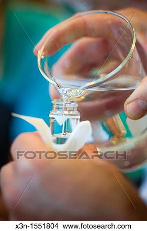 Picture - Hands pouring water from beaker into a test tube in lab at UMCP Greenhouse. Fotosearch