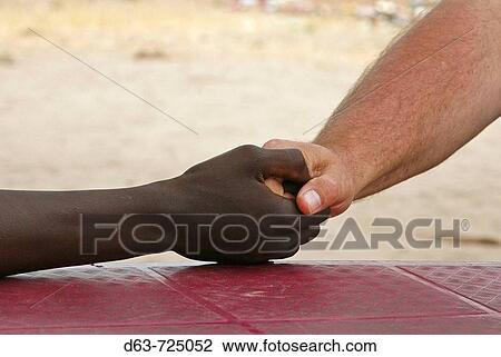 Handshake between a white and a black man. Nyangana, a small village and mission station in the north of the country on the Angolan border View Large Photo Image Stock Image - Handshake between a white and a black man. Nyangana, a small village and mission station in the north of the country on the Angolan border. Fotosearch
