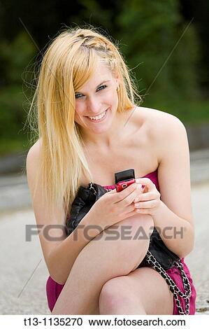Happy attractive young woman with a cellular phone in hand View Large Photo Image Stock Image - Happy attractive young woman with a cellular phone in hand. Fotosearch