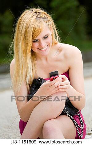 Happy attractive young woman with a cellular phone in hand View Large Photo Image Stock Photo - Happy attractive young woman with a cellular phone in hand. Fotosearch