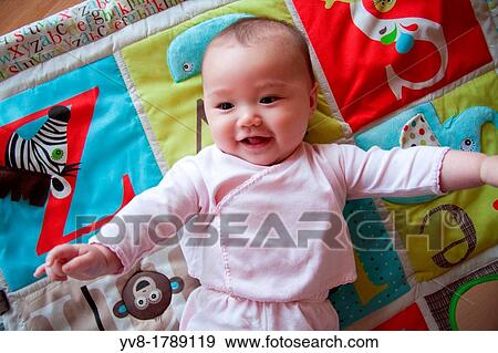 Stock Photo - Happy baby on colorful playmat. Fotosearch