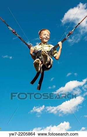 Happy boy jumping on a trampoline. View Large Photo Image Picture - Happy boy jumping on a trampoline.. Fotosearch