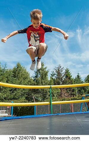 Happy boy jumping on a trampoline. View Large Photo Image Stock Image - Happy boy jumping on a trampoline.. Fotosearch