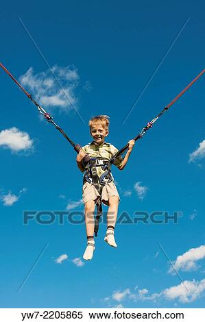 Stock Photography - Happy boy jumping on a trampoline.. Fotosearch