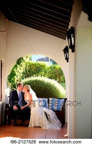 Stock Photograph - happy couple enjoying a quiet moment sitting on a couch after their wedding ceremony. Fotosearch