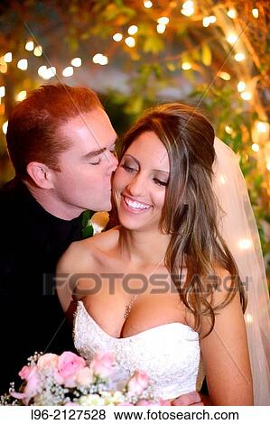 happy couple - groom kissing bride on cheek in a magical twinkle light setting at night View Large Photo Image Stock Photo - happy couple - groom kissing bride on cheek in a magical twinkle light setting at night. Fotosearch
