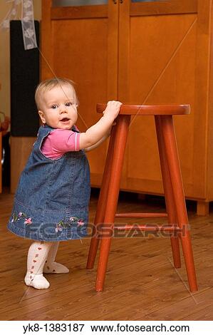 Happy Eight Month Old Infant Girl Standing by Stool Chair View Large Photo Image Stock Photo - Happy Eight Month Old Infant Girl Standing by Stool Chair. Fotosearch