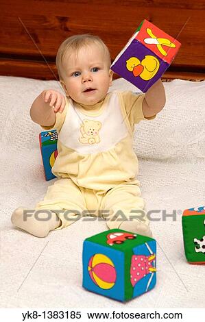 Stock Photography - Happy Eight Month Old Infant Girl Playing With Cubes on Bed. Fotosearch