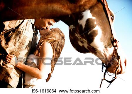 happy engaged couple riding horse on beach kissing embracing View Large Photo Image Picture - happy engaged couple riding horse on beach kissing embracing. Fotosearch