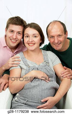 Happy family with Young woman expecting a baby in grey, holding her belly View Large Photo Image Stock Photo - Happy family with Young woman expecting a baby in grey, holding her belly. Fotosearch