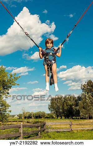 Stock Image - Happy girl jumping on a trampoline.. Fotosearch