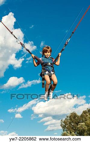 Stock Image - Happy girl jumping on a trampoline.. Fotosearch