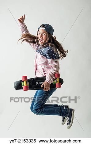 Stock Photography - Happy girl jumping with a skateboard. Fotosearch