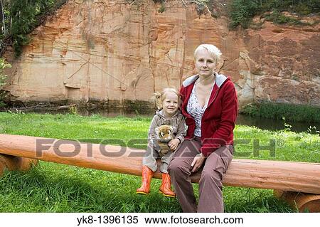 Happy Kid Girl Sitting with Mother on Wooden Tree Trunk Bench by Sandstone Outcrop View Large Photo Image Stock Photography - Happy Kid Girl Sitting with Mother on Wooden Tree Trunk Bench by Sandstone Outcrop. Fotosearch