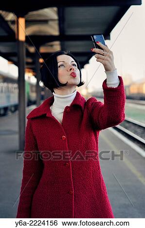 Stock Photograph - Happy mid adult woman taking self-portrait photograph using smartphone.. Fotosearch