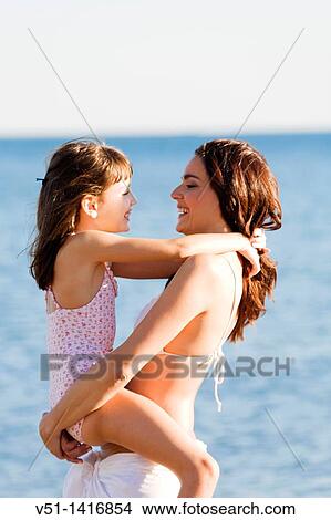 Happy mother carrying her daughter at the beach View Large Photo Image Picture - Happy mother carrying her daughter at the beach. Fotosearch